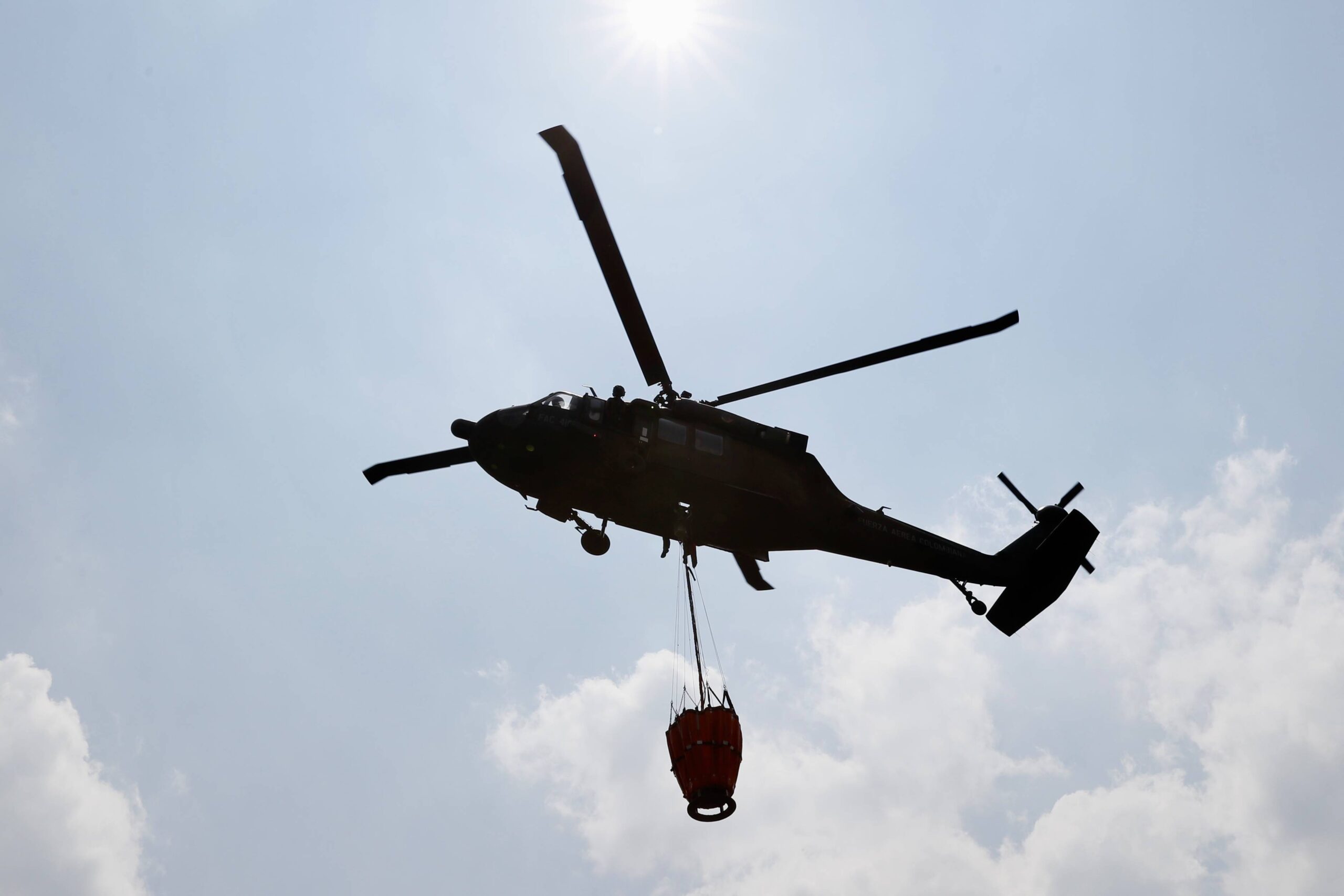 Un helicóptero de la Fuerza Aeroespacial Colombiana (FAC) reabastece con agua el sistema Bambi Bucket para combatir los incendios de los cerros orientales, en Bogotá (Colombia).